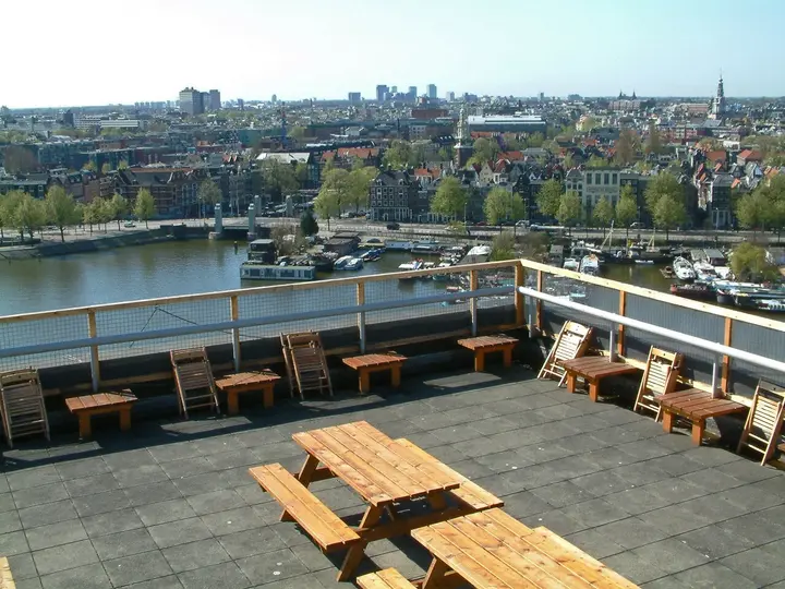 Rooftop terrace overlooking the water and buildings of Amsterdam.