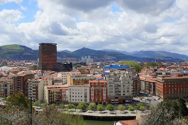 Bilbao apartment buildings with green hills beyond.