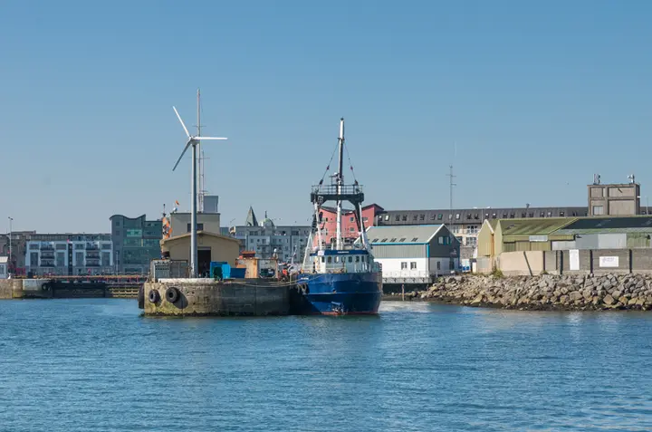 Fishing boats moored beside buildings in Galway Harbour.