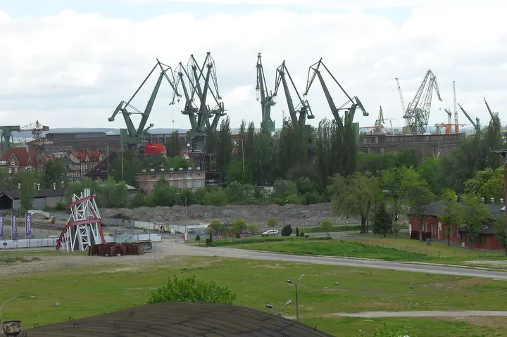 Dock cranes above buildings and trees in Gdańsk.