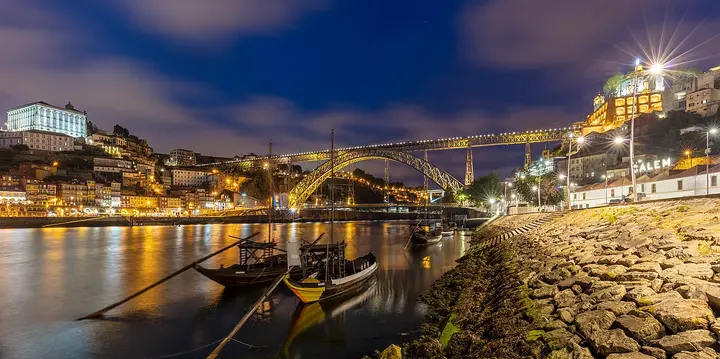 Illuminated bridge and hillside buildings beside the river in Porto.