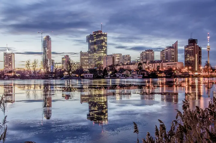 Vienna buildings reflected in the water beneath a cloudy sky.